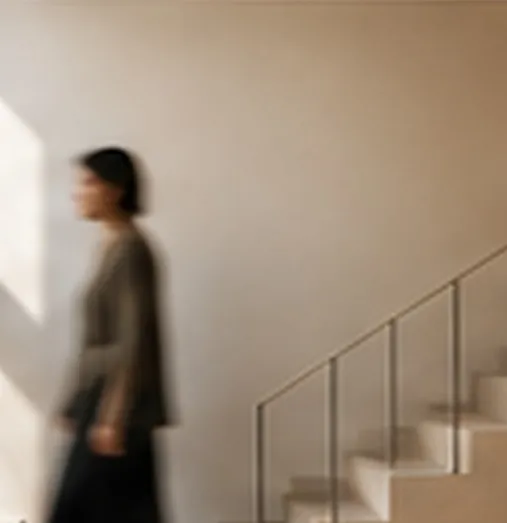 Une silhouette passe devant un escalier dans une lumière douce